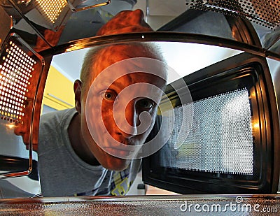 Man looking Inside microwave Stock Photo