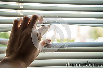 Man is looking out through jalousie or blinds. Privacy concept Stock Photo