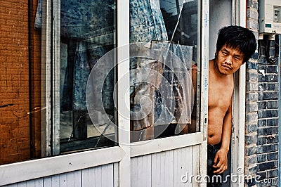 Man looking outside of his home to the street in a typical city hutong Editorial Stock Photo
