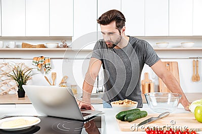 Man looking recipe on laptop in kitchen at home Stock Photo