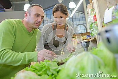 Man looking at vegetables with shop asistant Stock Photo