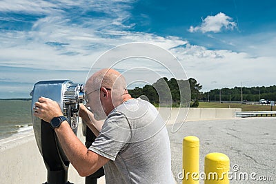 Man looks through Coin binoculars at ocean Stock Photo