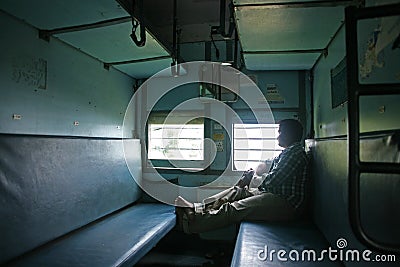 Man looks out the window in a classic Indian Railways scene in a second class carriage in late 2015 Editorial Stock Photo