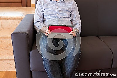 Man looks at the tablet sitting on the sofa Stock Photo