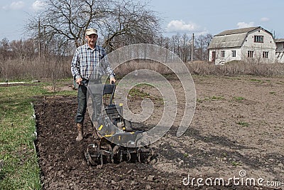 Man loosens the soil cultivator Stock Photo