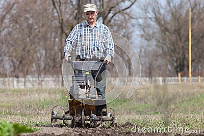 Man loosens the soil cultivator Stock Photo