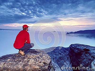 Man lost in thick mist rocks. Hiker climbed up alone to exposed summit Stock Photo