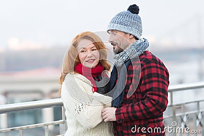 Man loves rude woman closing his eyes. Guy in rad jacket and scurf happy to woman in red scurf. Aged couple meet in city. Stock Photo