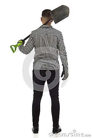 Man in lumberjack shirt is standing with spade on his shoulder. Rear view. Studio shot Stock Photo