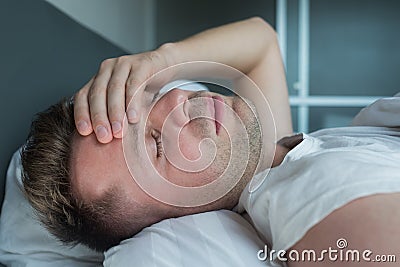 Man lying in bed at home suffering from headache or hangover Stock Photo