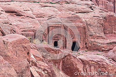 The man-made caves carved in red mountain in Petra - the capital of the Nabatean kingdom in Wadi Musa city in Jordan Editorial Stock Photo