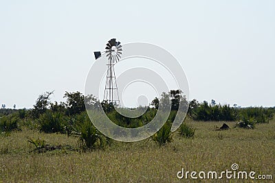 A man-made waterhole with a windmill to give water to the wildlife.This drinking hole is far from rivers. Stock Photo