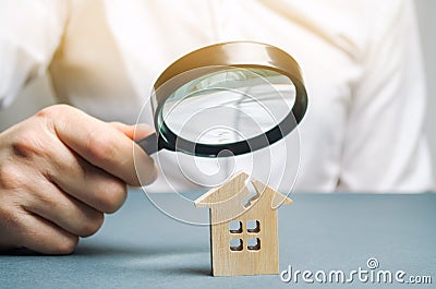 A man with a magnifying glass looks at a house with a crack. Damage assessment home and insurance risks Stock Photo