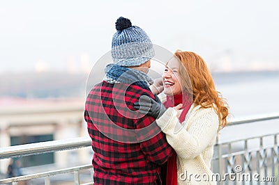 Man makes funny ginger woman in red scurf. Guy cares about woman. Woman happy to meet man in city. Stock Photo