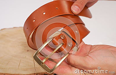 Man makes by hands leather belt with buckle. handmade hobby. young man resting by manufacture his designer belts. man with a screw Stock Photo