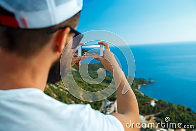 Man makes photos by a smartphone on the background of sea coast, Stock Photo