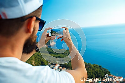 Man makes photos by a smartphone on the background of sea coast, Adriatic sea Stock Photo