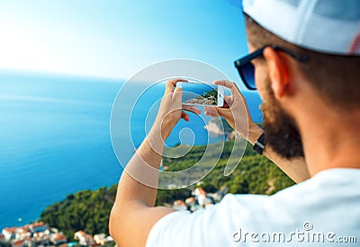 Man makes photos by a smartphone on the background of sea coast, Adriatic sea Stock Photo