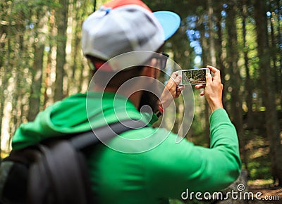 Man makes photos on a smartphone in the coniferous forest in the Stock Photo