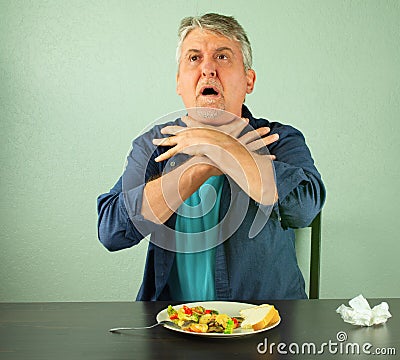 Man making the international sign for `I`m choking` as he chokes on food Stock Photo