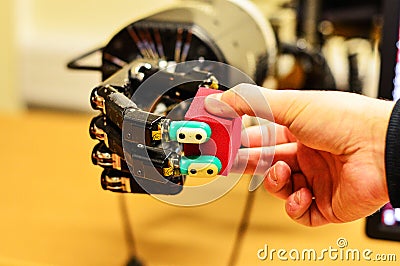 Man and Mechanical Hand Holding a Red Cube in the Research Laboratory Stock Photo