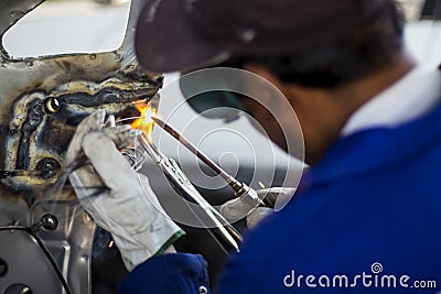 Man mechanical worker repairing a car body in a garage - Safety at work with protection wear. Welding work Stock Photo