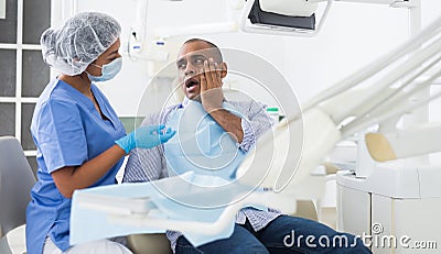 Man in chair complains of toothache to dentist Stock Photo