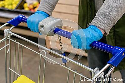 A man in medical gloves holds a grocery cart, close-up. No face visible Stock Photo