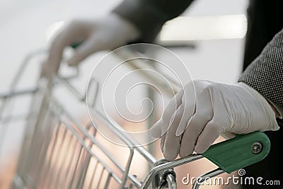 A man in medical gloves holds a grocery cart, close-up, no face Stock Photo