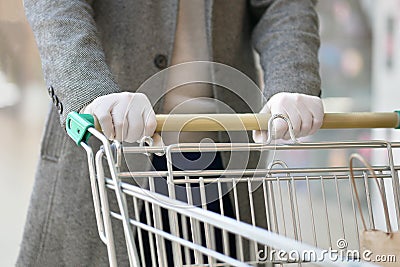 A man in medical gloves holds a grocery cart, close-up, no face Stock Photo