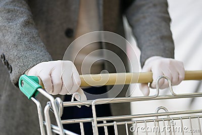 A man in medical gloves holds a grocery cart, close-up, no face Stock Photo