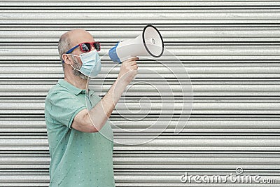 Man with medical mask screaming with megaphone Stock Photo