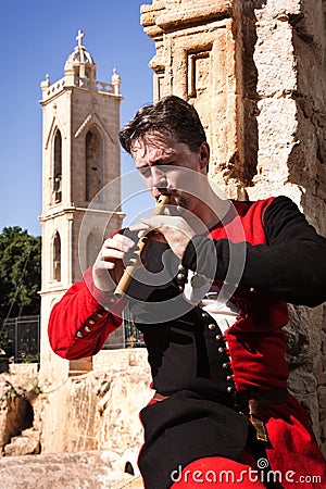 Man in a medieval suit plays a flute Stock Photo