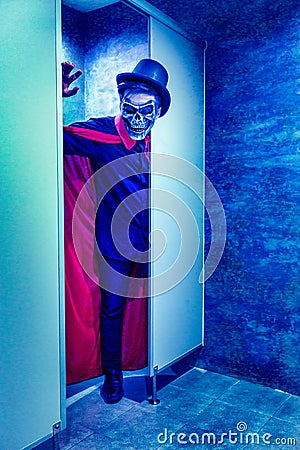 A man with metal skull mask and red cloak in blue light toilet in halloween party Stock Photo