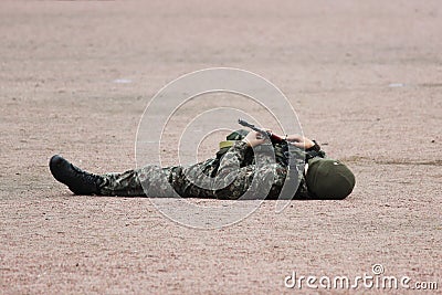 Man in Military camouflage clothing and a mask lying on his back the sand with machine guns in hand during the demonstration pe Stock Photo