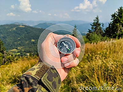Man in military clothes holding a compass in a hand on the carpathian mountains background Stock Photo