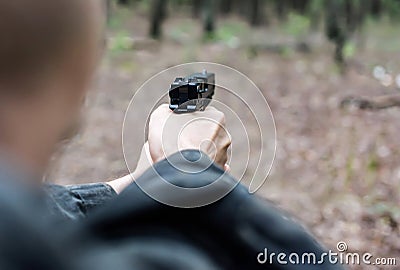 A man in military clothing is aiming with a pistol Stock Photo