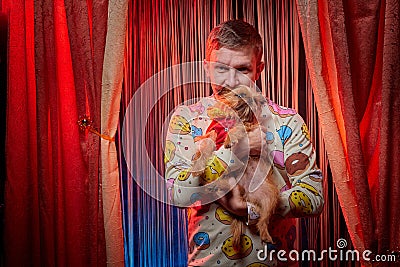 Man model with a small dog on the theater stage. Photo shoot in the circus style Stock Photo