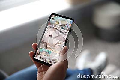 Man monitoring CCTV cameras on smartphone indoors, closeup. Home security system Stock Photo