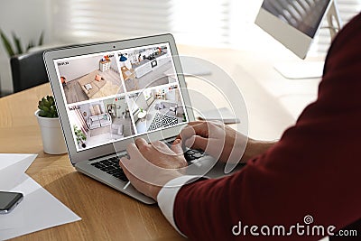 Man monitoring modern CCTV cameras at wooden table, closeup. Smart home security system Stock Photo