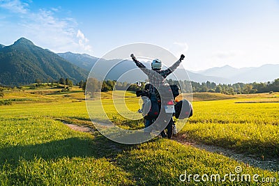 Man motorcyclist happy destination scene. Motorcycle adventure. Alpine mountains on background. Biker lifestyle, world traveler. Stock Photo