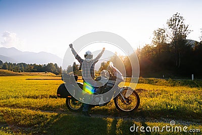 Man motorcyclist happy destination scene. Motorcycle adventure. Alpine mountains on background. Biker lifestyle, world traveler. Stock Photo