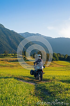 Man motorcyclist ride touring motorcycle in action. Alpine mountains on background. Biker lifestyle, world traveler. Summer sunny Stock Photo