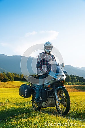 Man motorcyclist ride touring motorcycle in action. Alpine mountains on background. Biker lifestyle, world traveler. Summer sunny Stock Photo