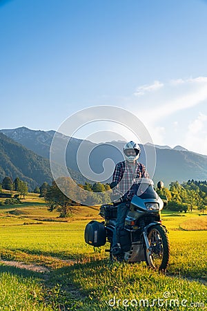 Man motorcyclist ride touring motorcycle in action. Alpine mountains on background. Biker lifestyle, world traveler. Summer sunny Stock Photo