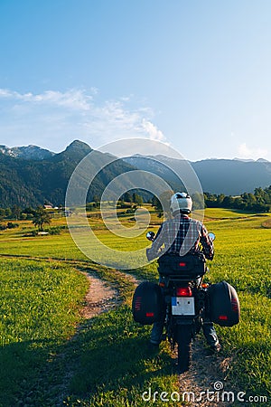 Man motorcyclist ride touring motorcycle. Alpine mountains on background. Biker lifestyle, world traveler. Summer sunny sunset day Stock Photo