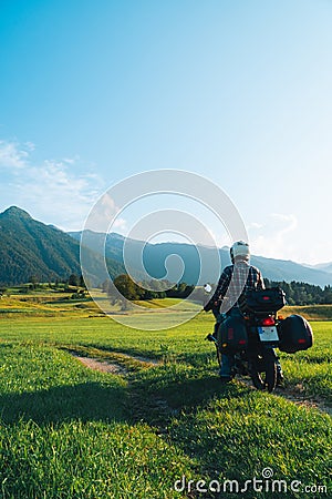 Man motorcyclist ride touring motorcycle. Alpine mountains on background. Biker lifestyle, world traveler. Summer sunny sunset day Stock Photo