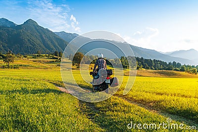 Man motorcyclist ride touring motorcycle. Alpine mountains on background. Biker lifestyle, world traveler. Summer sunny sunset day Stock Photo