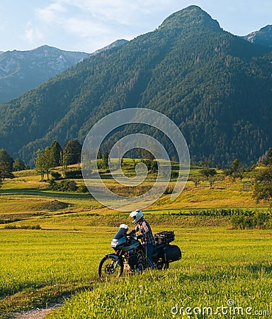 Man motorcyclist ride touring motorcycle. Alpine mountains on background. Biker lifestyle, world traveler. Summer sunny sunset day Stock Photo