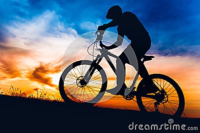 Man on mountain bike at sunset, riding bicycle on hills Stock Photo